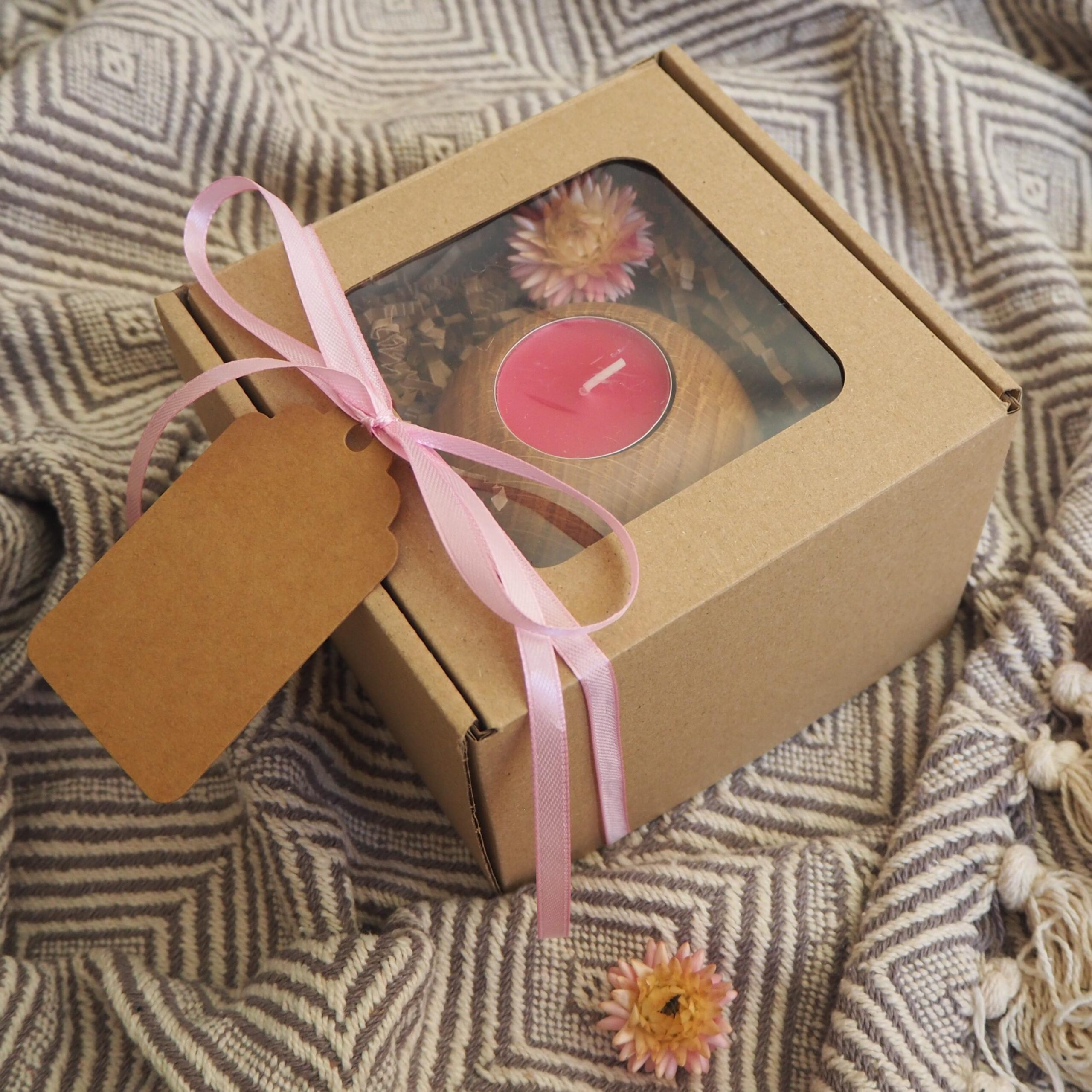Zestaw prezentowy w eko pudełku z drewnianym świecznikiem na tealighty o kształcie kuli z różową świecą tealight i suszonym kwiatem. Opleciony różową wstążką.
